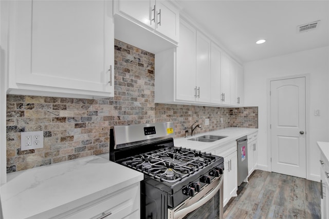 kitchen featuring light stone counters, white cabinets, stainless steel appliances, light hardwood / wood-style flooring, and sink