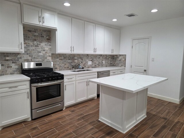 1307 Brooks Ave, Rosenberg, TX 77471 - kitchen featuring stainless steel appliances, a sink, dark wood-type flooring, white cabinetry, and decorative backsplash