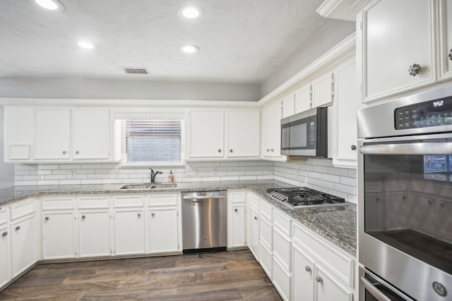 kitchen with white cabinetry, dark stone counters, dark wood-type flooring, sink, and stainless steel appliances