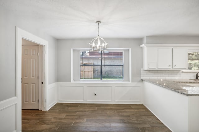 unfurnished dining area with dark wood-type flooring, a wealth of natural light, a chandelier, and sink