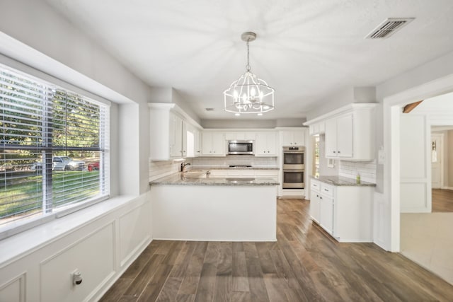 kitchen featuring kitchen peninsula, stainless steel appliances, white cabinets, dark wood-type flooring, and decorative backsplash