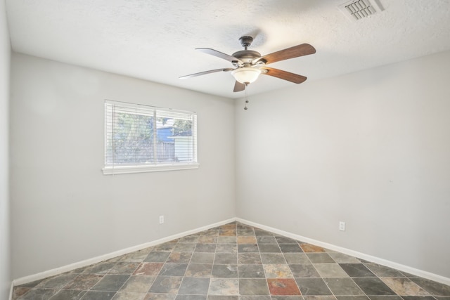 unfurnished room with ceiling fan and a textured ceiling