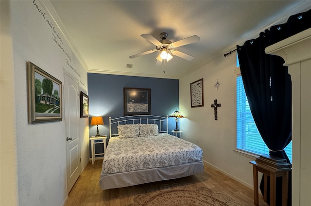 bedroom featuring wood-type flooring, ornamental molding, and ceiling fan