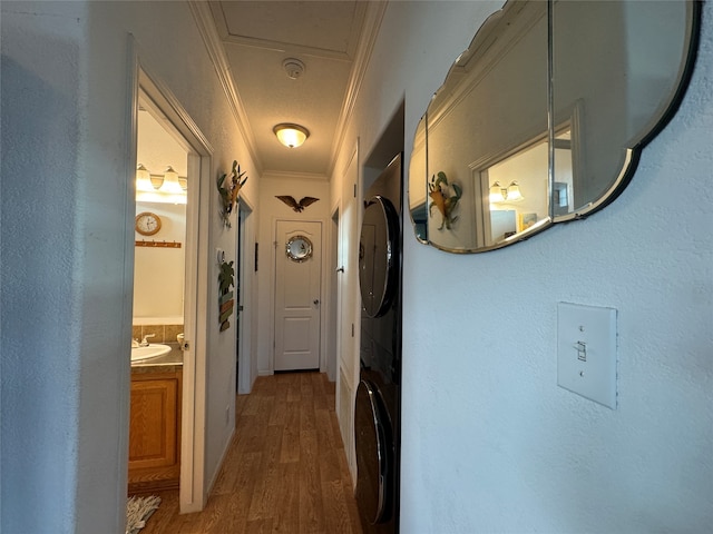 corridor with stacked washer and dryer, ornamental molding, dark hardwood / wood-style floors, and sink