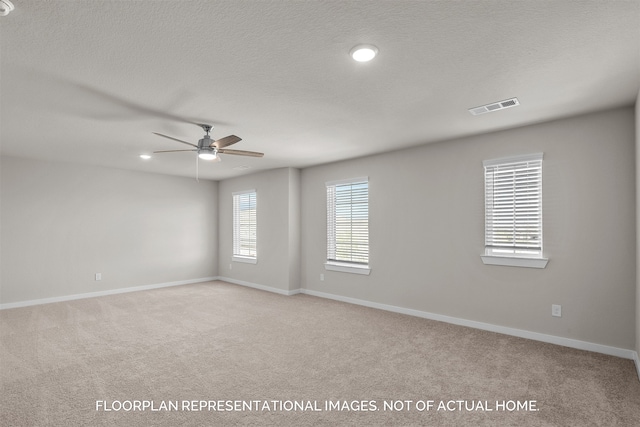 spare room with ceiling fan, light colored carpet, and a textured ceiling