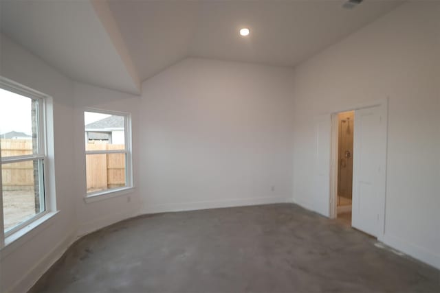 unfurnished room featuring vaulted ceiling and plenty of natural light