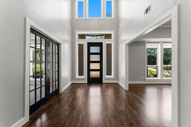 foyer entrance with french doors, a towering ceiling, and dark hardwood / wood-style flooring