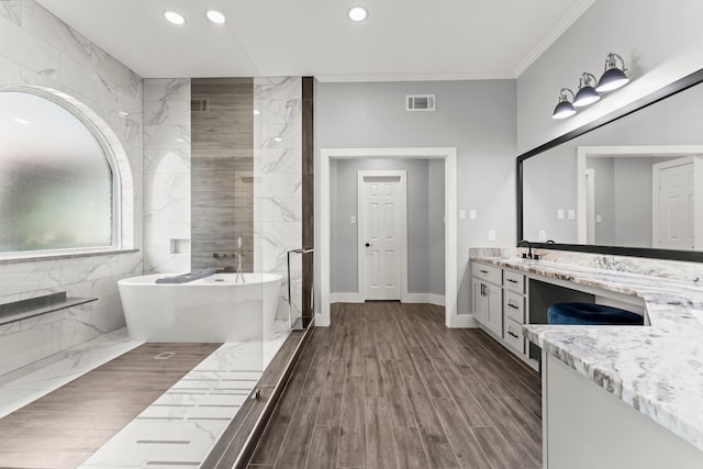 bathroom with a bath, vanity, tile walls, and ornamental molding