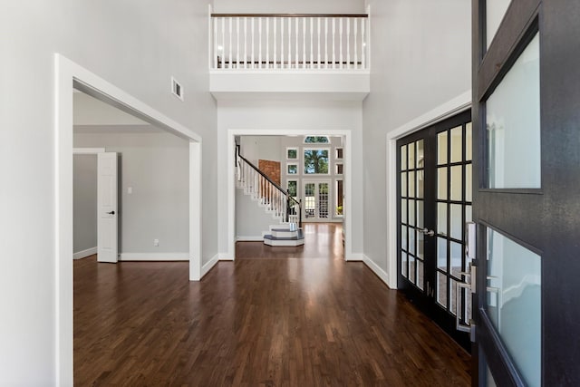 foyer entrance featuring french doors, a towering ceiling, and dark hardwood / wood-style flooring