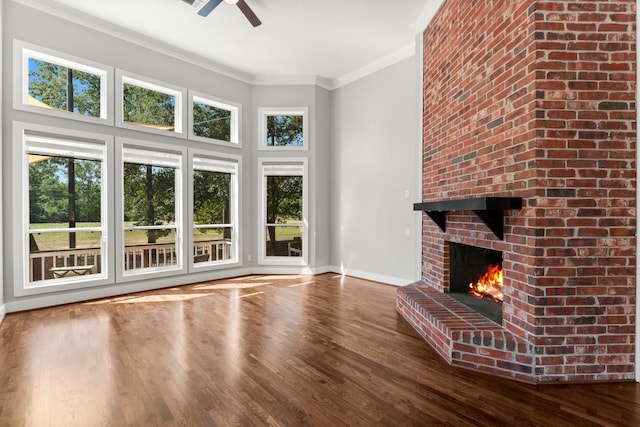 unfurnished living room with a brick fireplace, ceiling fan, wood-type flooring, and ornamental molding