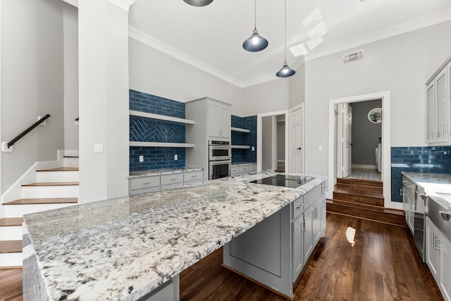 kitchen featuring decorative backsplash, decorative light fixtures, black electric cooktop, and a spacious island