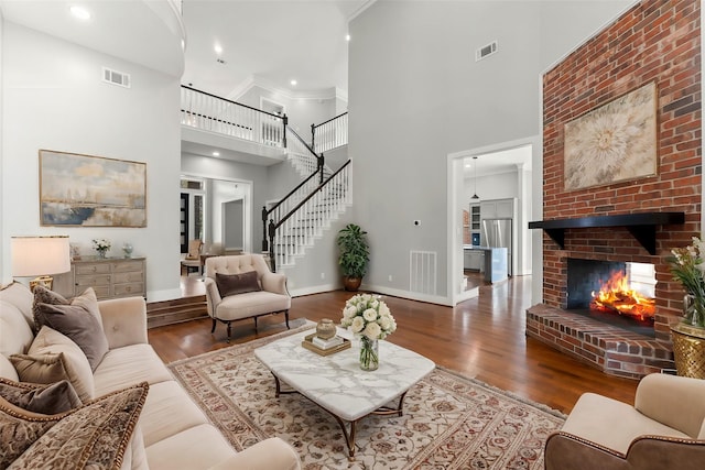 living room with a fireplace, a high ceiling, dark hardwood / wood-style flooring, and ornamental molding