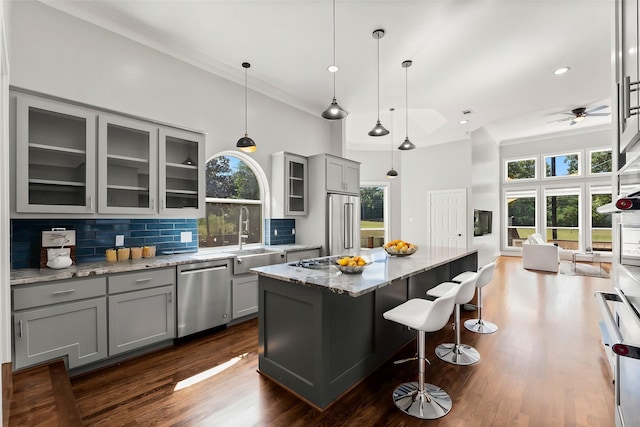 kitchen with gray cabinetry, light stone countertops, a center island, sink, and stainless steel appliances