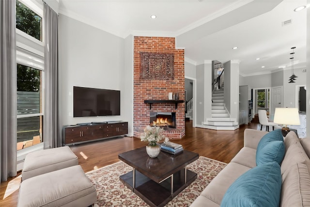 living room featuring wood-type flooring, ornamental molding, and a fireplace