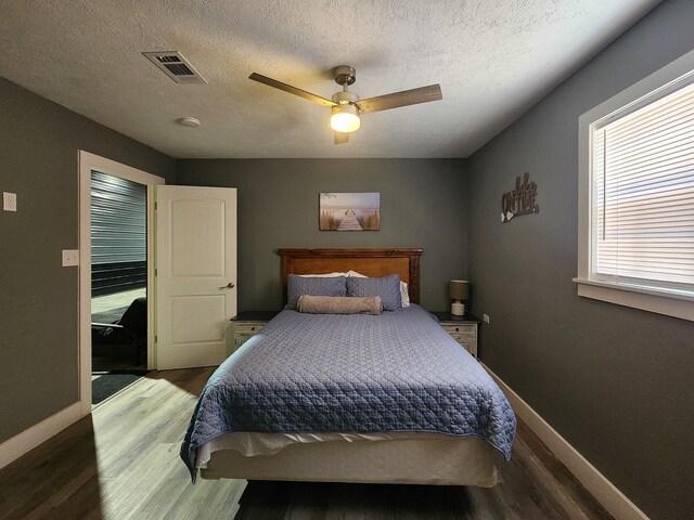 bedroom featuring ceiling fan, dark wood-type flooring, and a textured ceiling