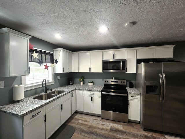 kitchen with dark hardwood / wood-style flooring, sink, stainless steel appliances, and white cabinets