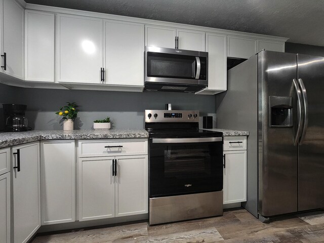 kitchen featuring white cabinets, light wood-type flooring, and appliances with stainless steel finishes