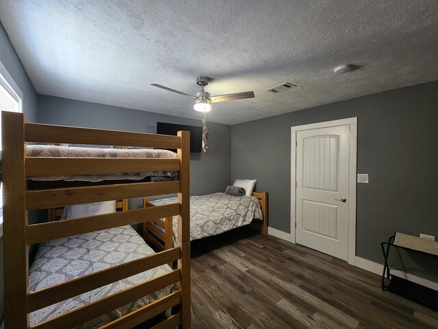 bedroom with ceiling fan, a textured ceiling, and dark hardwood / wood-style flooring