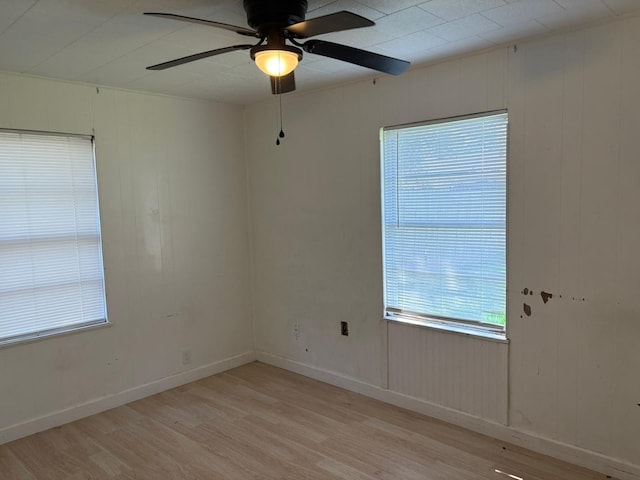 spare room with wooden walls, ceiling fan, and light hardwood / wood-style flooring