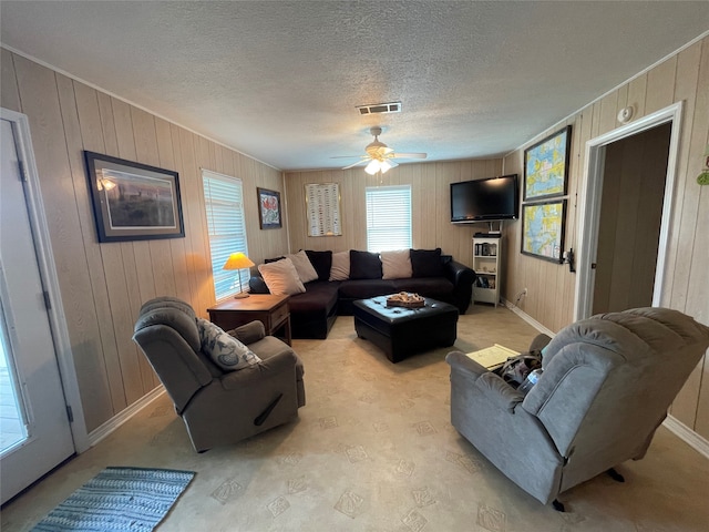 living room with a textured ceiling, wood walls, and ceiling fan