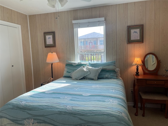 bedroom featuring carpet, wooden walls, ceiling fan, and a closet