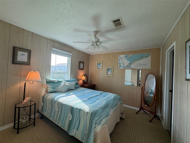 bedroom featuring a textured ceiling, carpet, wooden walls, and ceiling fan