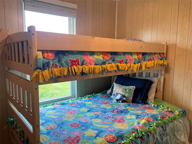 bedroom featuring wooden walls and multiple windows