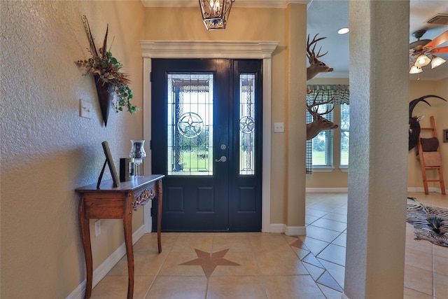 tiled foyer featuring a healthy amount of sunlight, crown molding, and ceiling fan