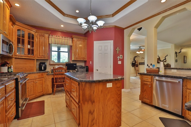 kitchen featuring ceiling fan with notable chandelier, a kitchen island, ornamental molding, and stainless steel appliances