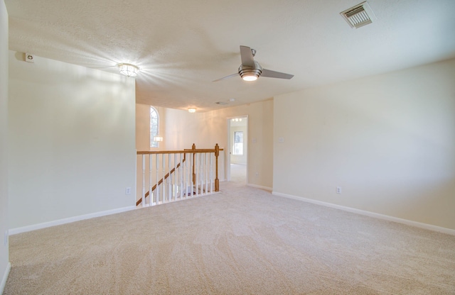 carpeted spare room featuring a textured ceiling and ceiling fan