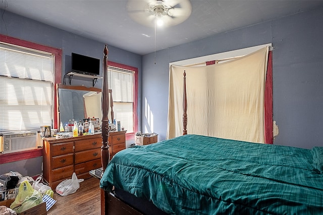 bedroom with cooling unit, ceiling fan, multiple windows, and hardwood / wood-style floors