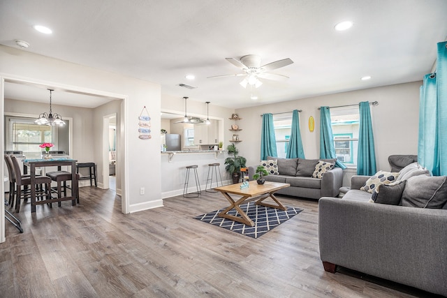 living room featuring a healthy amount of sunlight, ceiling fan with notable chandelier, and wood-type flooring