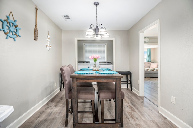 dining area with wood-type flooring, an inviting chandelier, and plenty of natural light