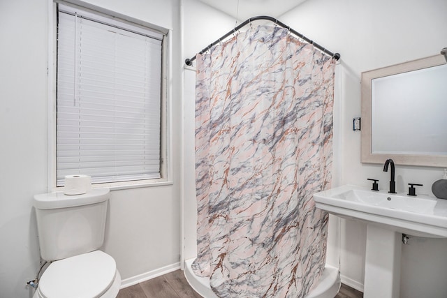 bathroom featuring curtained shower, hardwood / wood-style floors, and toilet