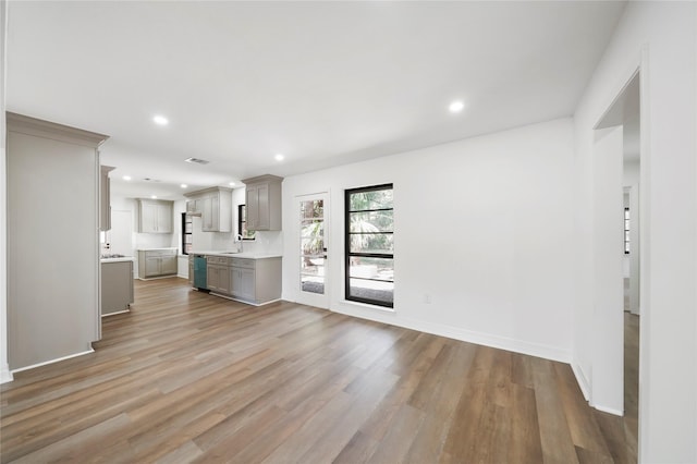 unfurnished living room featuring sink and light hardwood / wood-style floors