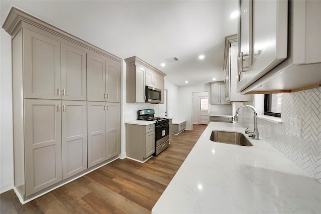 kitchen featuring light stone countertops, gas range, dark wood-type flooring, sink, and gray cabinets