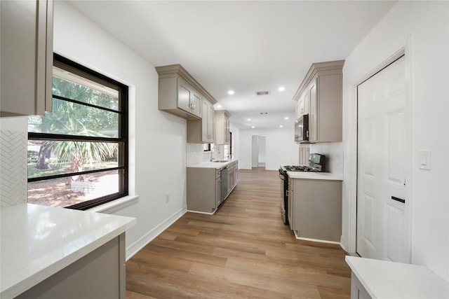 kitchen featuring gray cabinetry, sink, gas range oven, and light hardwood / wood-style flooring