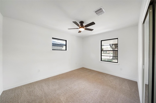 carpeted spare room with a wealth of natural light and ceiling fan