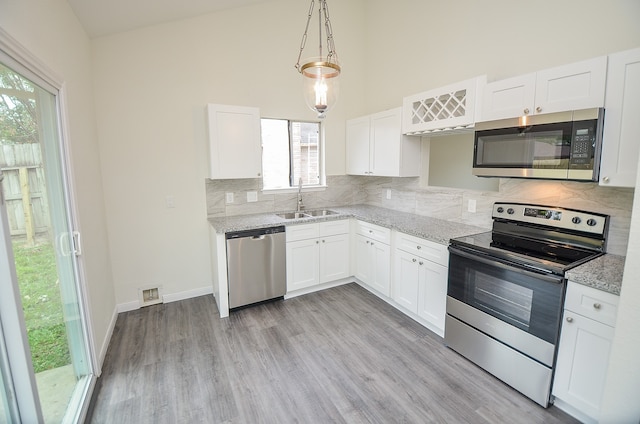 kitchen featuring sink, light hardwood / wood-style flooring, white cabinetry, appliances with stainless steel finishes, and light stone countertops