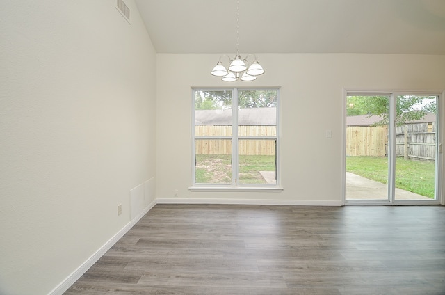 unfurnished dining area featuring a chandelier, vaulted ceiling, and hardwood / wood-style flooring