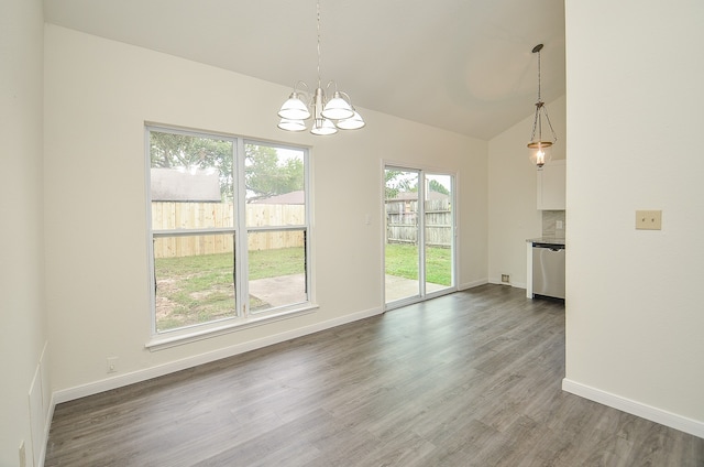 unfurnished dining area with an inviting chandelier, hardwood / wood-style flooring, and vaulted ceiling