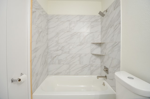 bathroom featuring tiled shower / bath combo and toilet