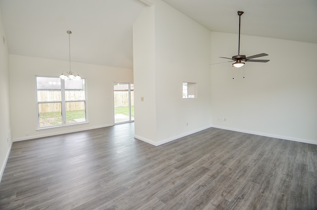 unfurnished living room with ceiling fan with notable chandelier, dark wood-type flooring, and high vaulted ceiling