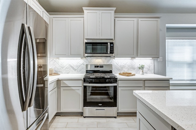 kitchen featuring decorative backsplash, stainless steel appliances, and white cabinetry