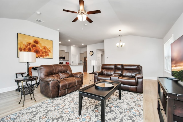 living room with sink, ceiling fan with notable chandelier, light hardwood / wood-style floors, and vaulted ceiling