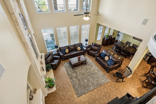 tiled living room featuring ceiling fan, a healthy amount of sunlight, and a high ceiling