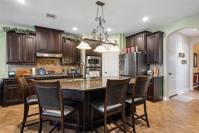 kitchen featuring appliances with stainless steel finishes, sink, dark brown cabinets, and an island with sink