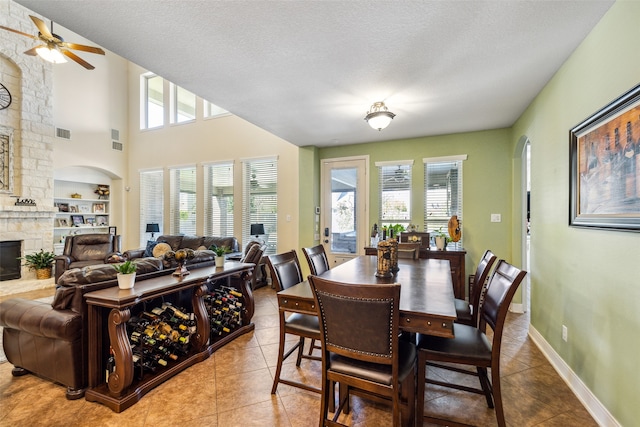 tiled dining space featuring a textured ceiling, ceiling fan, built in features, and a fireplace