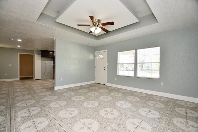 spare room with a raised ceiling and ceiling fan