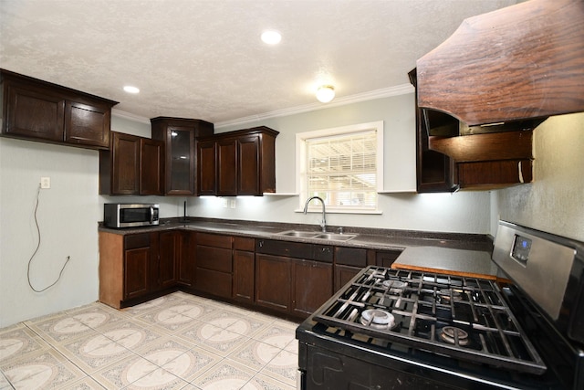 kitchen featuring ornamental molding, black range with gas stovetop, dark brown cabinetry, sink, and range hood